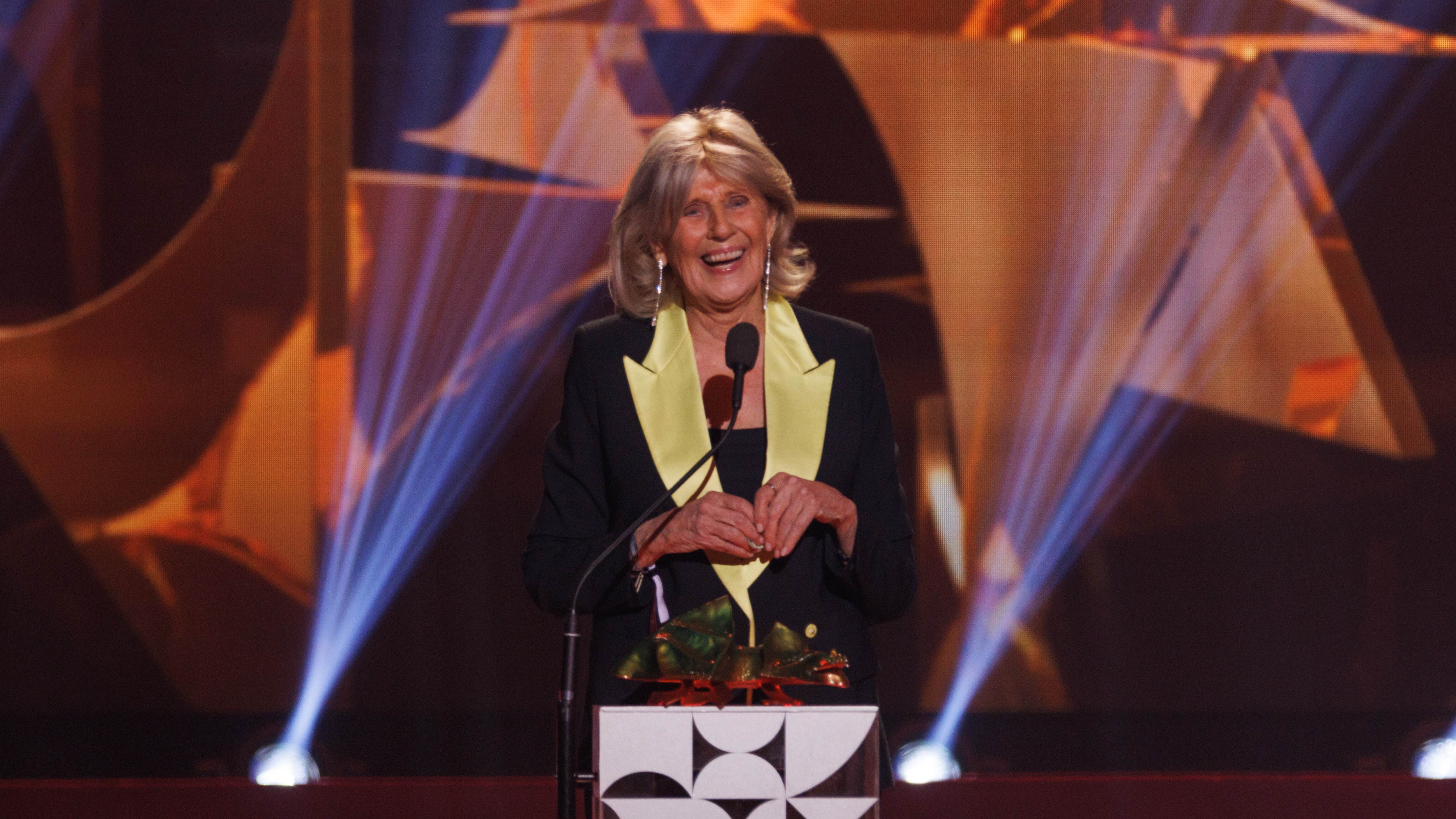 En glad kvinna står på scen.
